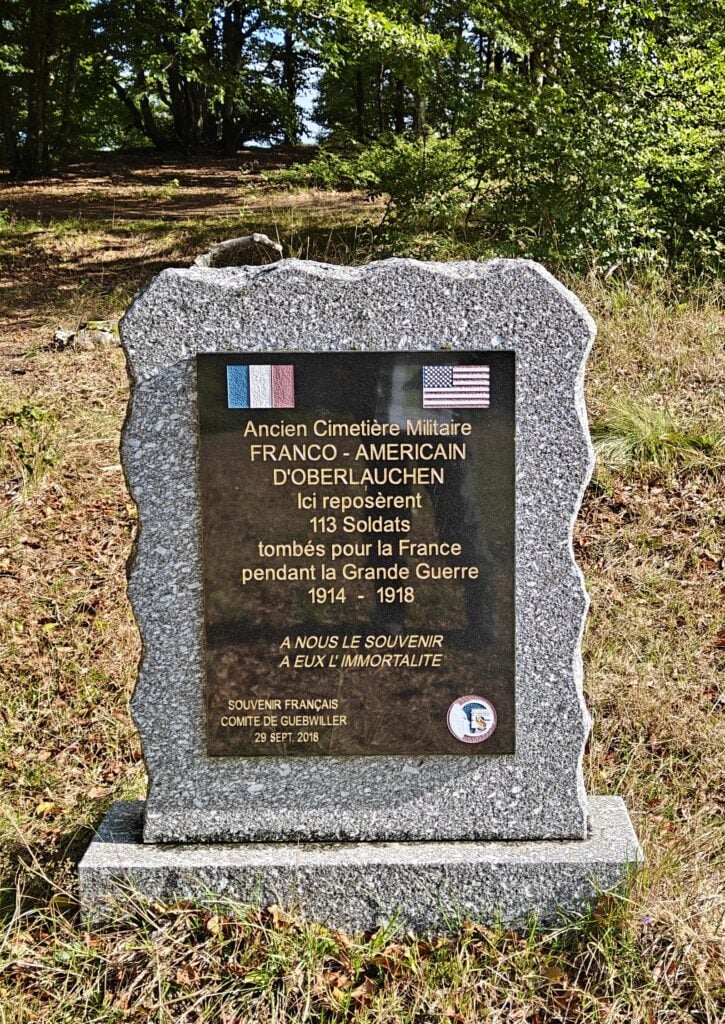 A headstone with the French and American flags markign the former cemetary. 